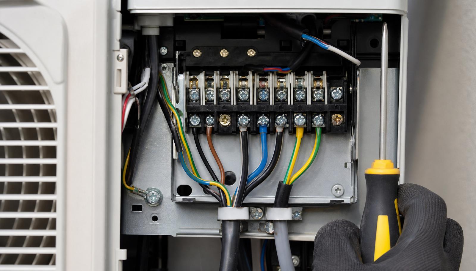Painel elétrico da unidade condensadora aberto, mostrando o bloco de terminais numerados de ligação com fios coloridos
