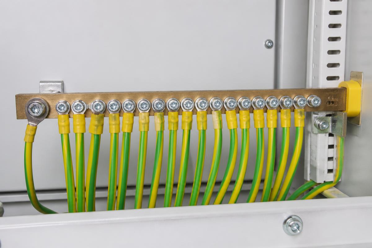 Barramento de terra dentro do quadro elétrico com cabos verde-amarelo parafusados