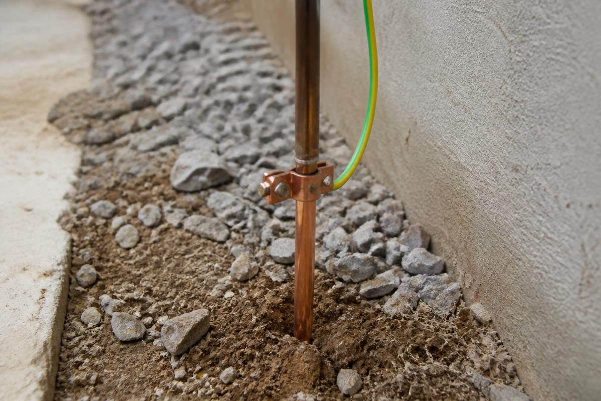 Haste de aterramento de cobre cravada no solo com conector e cabo verde-amarelo
