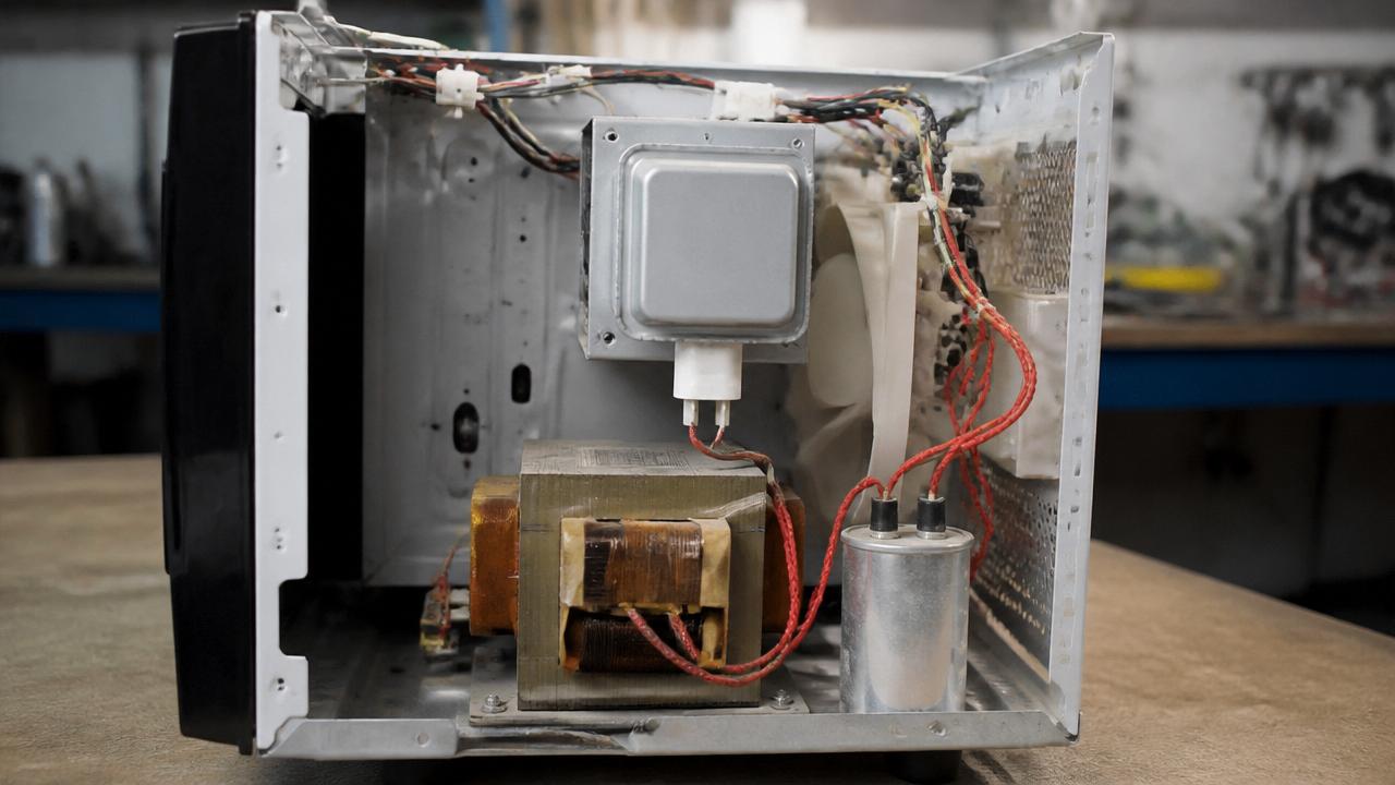Capacitor e transformador de alta tensão no interior de um micro-ondas — peças perigosas que guardam carga elétrica mesmo desligado
