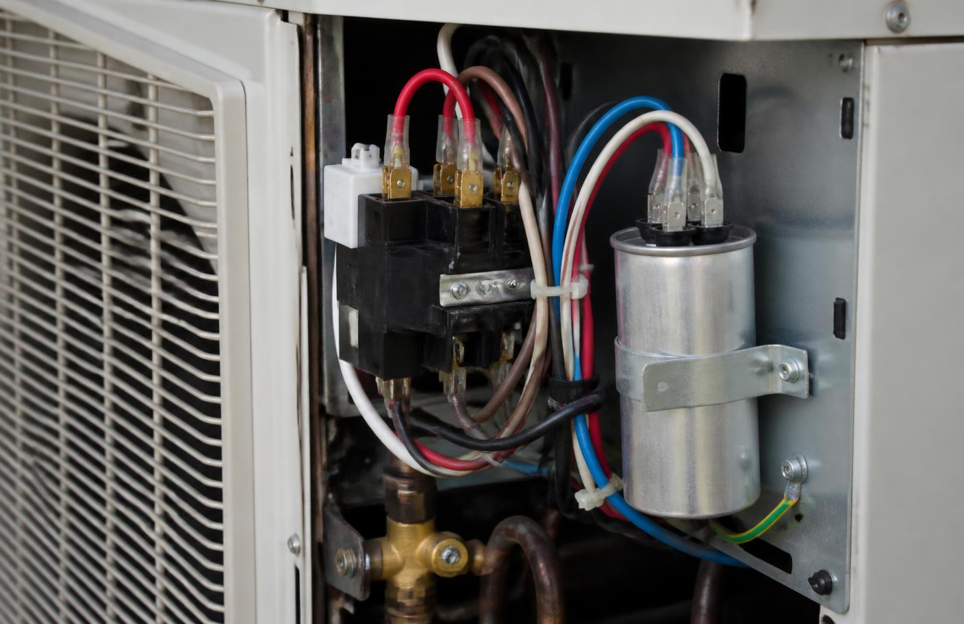 Capacitor cilíndrico preso por abraçadeira no compartimento elétrico de uma condensadora