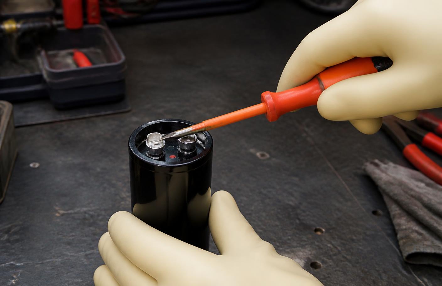 Descarga de capacitor com chave de fenda de cabo isolado e luvas de proteção