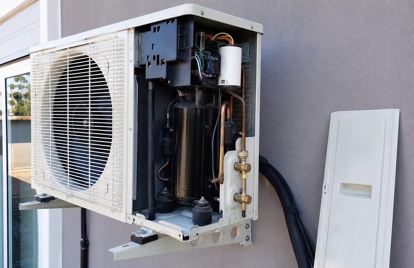 Condensadora de ar-condicionado aberta mostrando compressor, tubulação e serpentina interna
