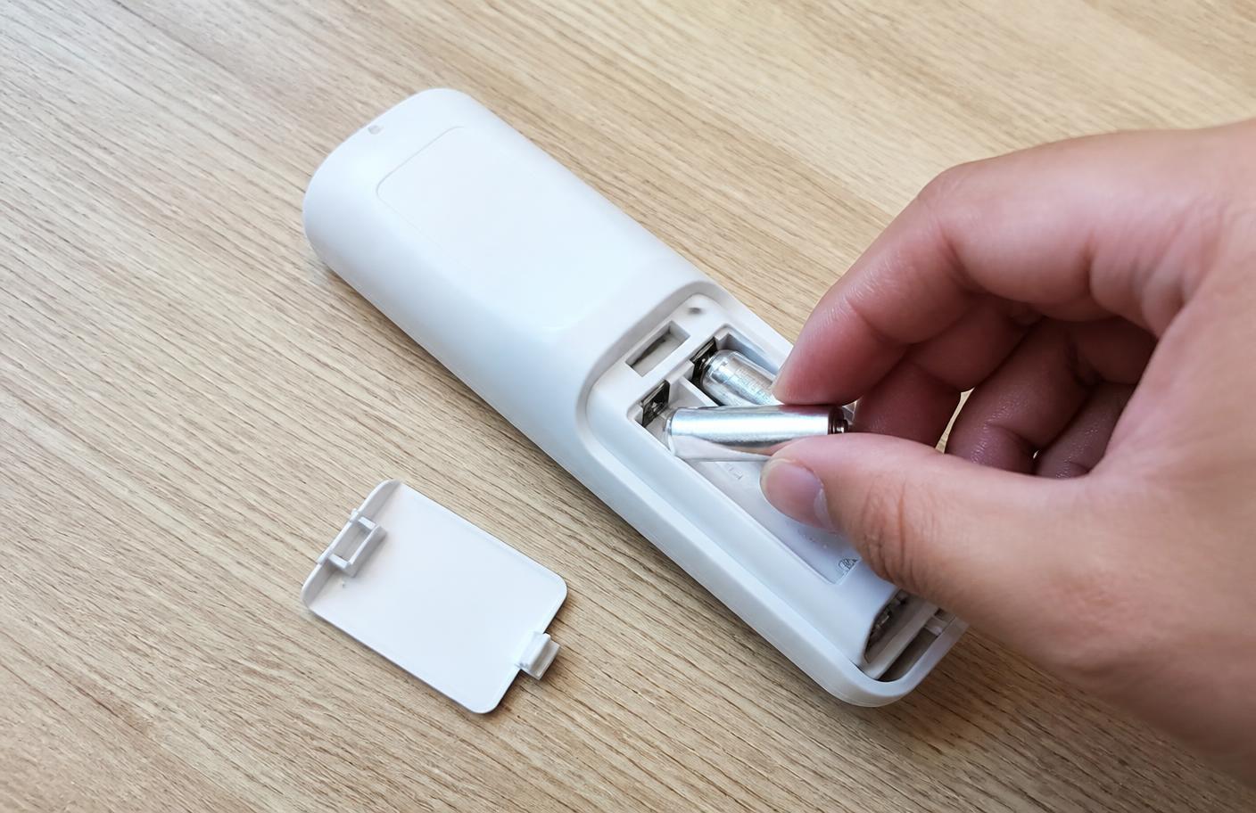 Troca das pilhas do controle remoto de ar-condicionado sobre mesa