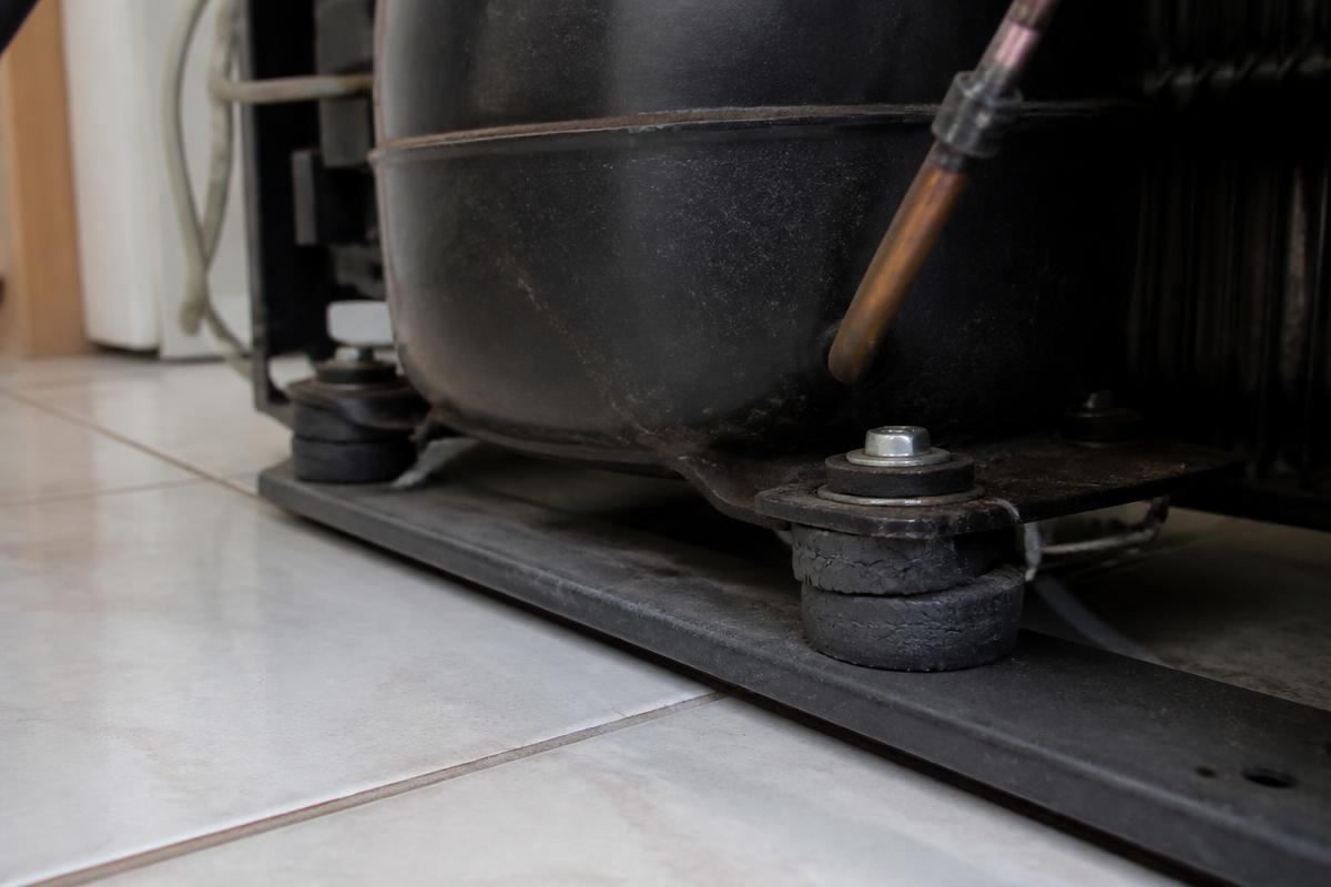 Base do compressor do freezer com os coxins de borracha de apoio ressecados e rachados
