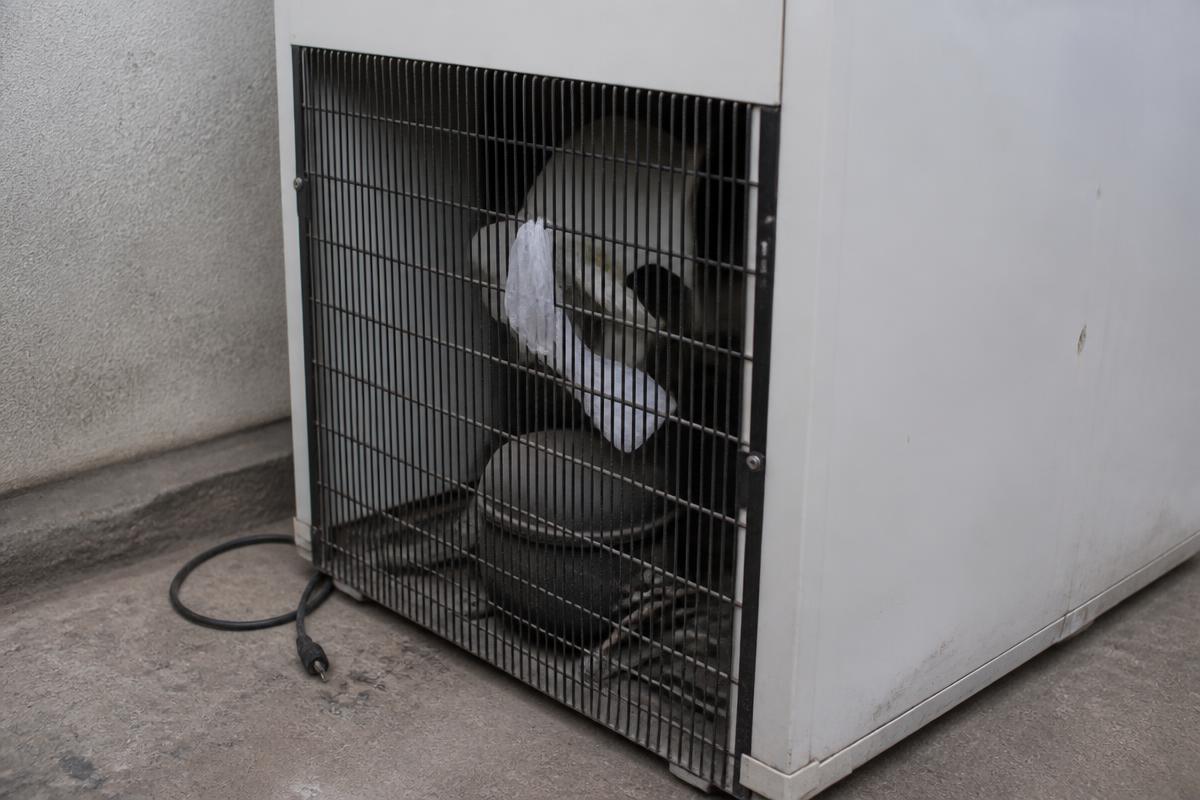 Pedaço de sacola plástica branca enroscado nas pás do ventilador externo da condensadora do freezer