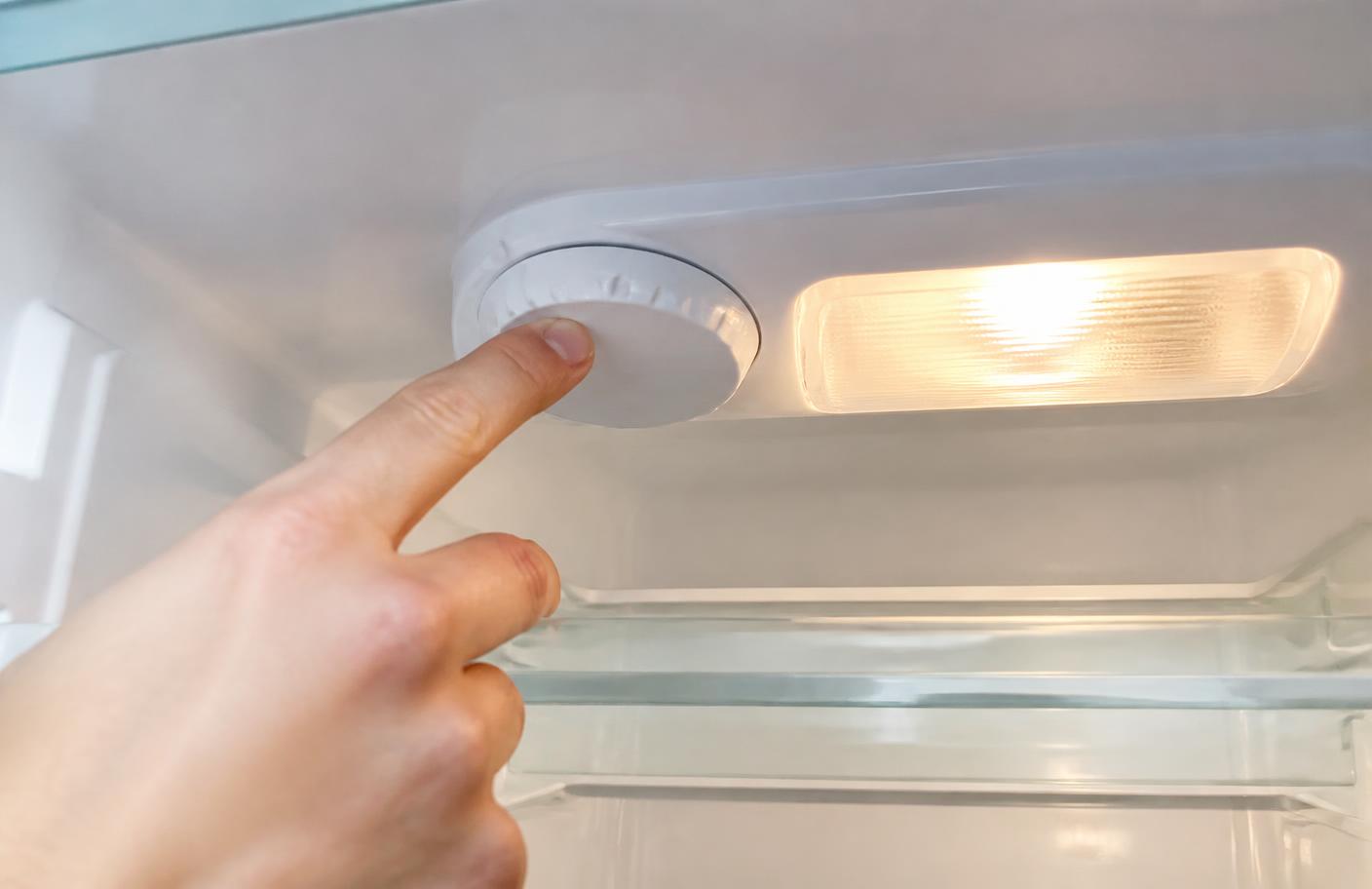 Dedo ajustando o botão de temperatura no interior de uma geladeira