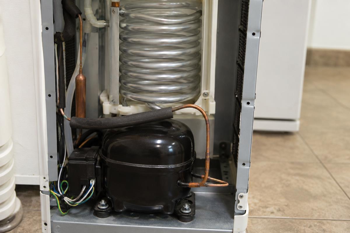 Componente de sistema de refrigeração eletrônico sendo inspecionado por técnico em bancada.