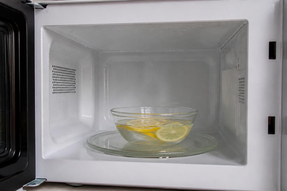 Tigela com água e limão soltando vapor dentro do micro-ondas para amolecer a gordura