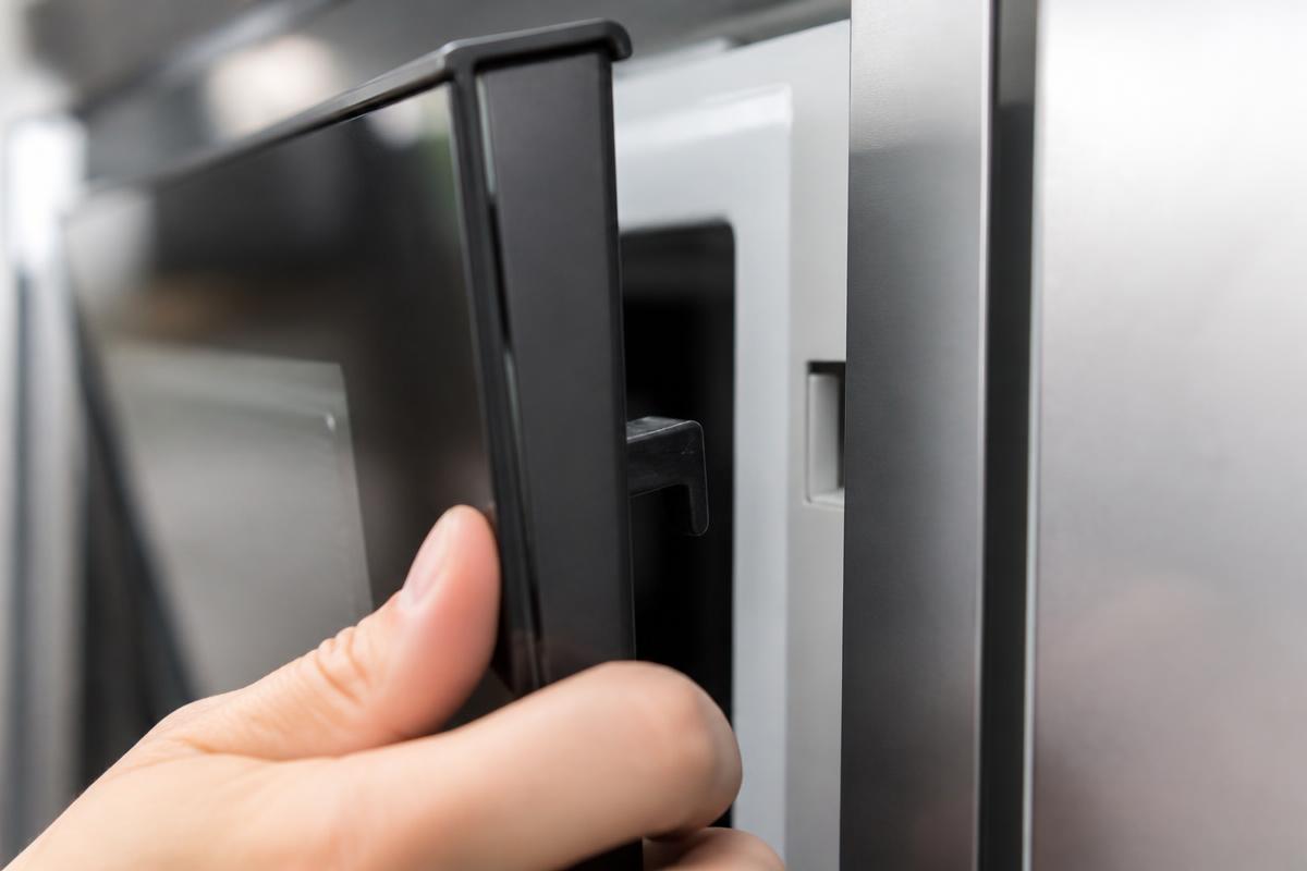 Porta do micro-ondas sendo fechada com firmeza até a trava acionar