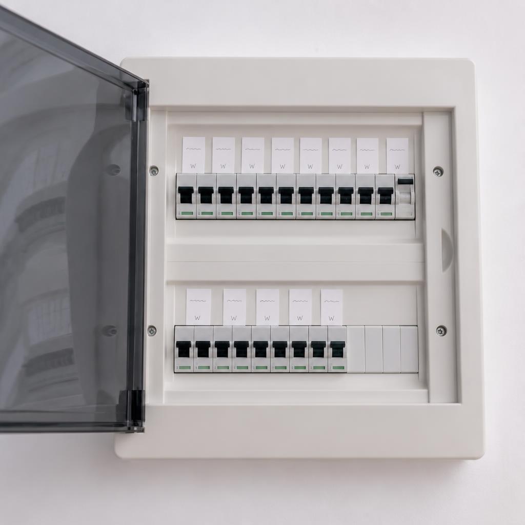 Quadro de distribuição elétrica residencial aberto mostrando linha organizada de disjuntores com etiquetas de identificação de circuito
