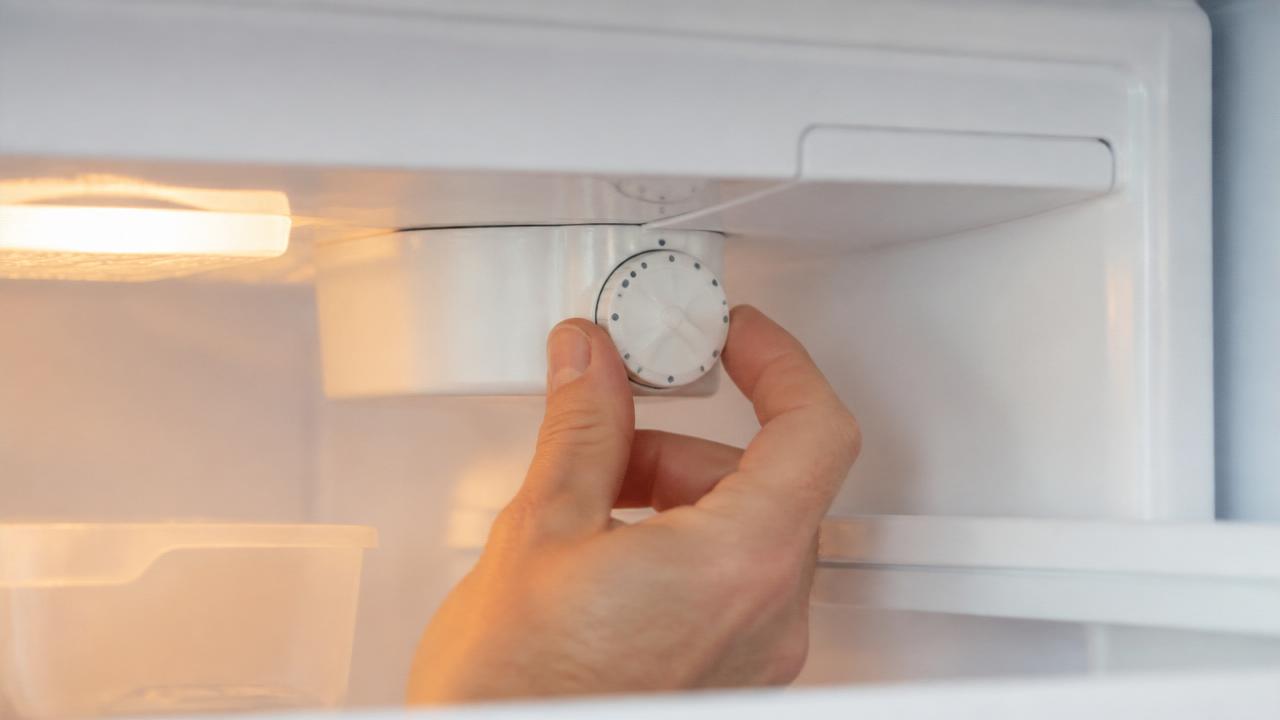 Botão de regulagem de temperatura no interior da geladeira sendo ajustado para um nível médio