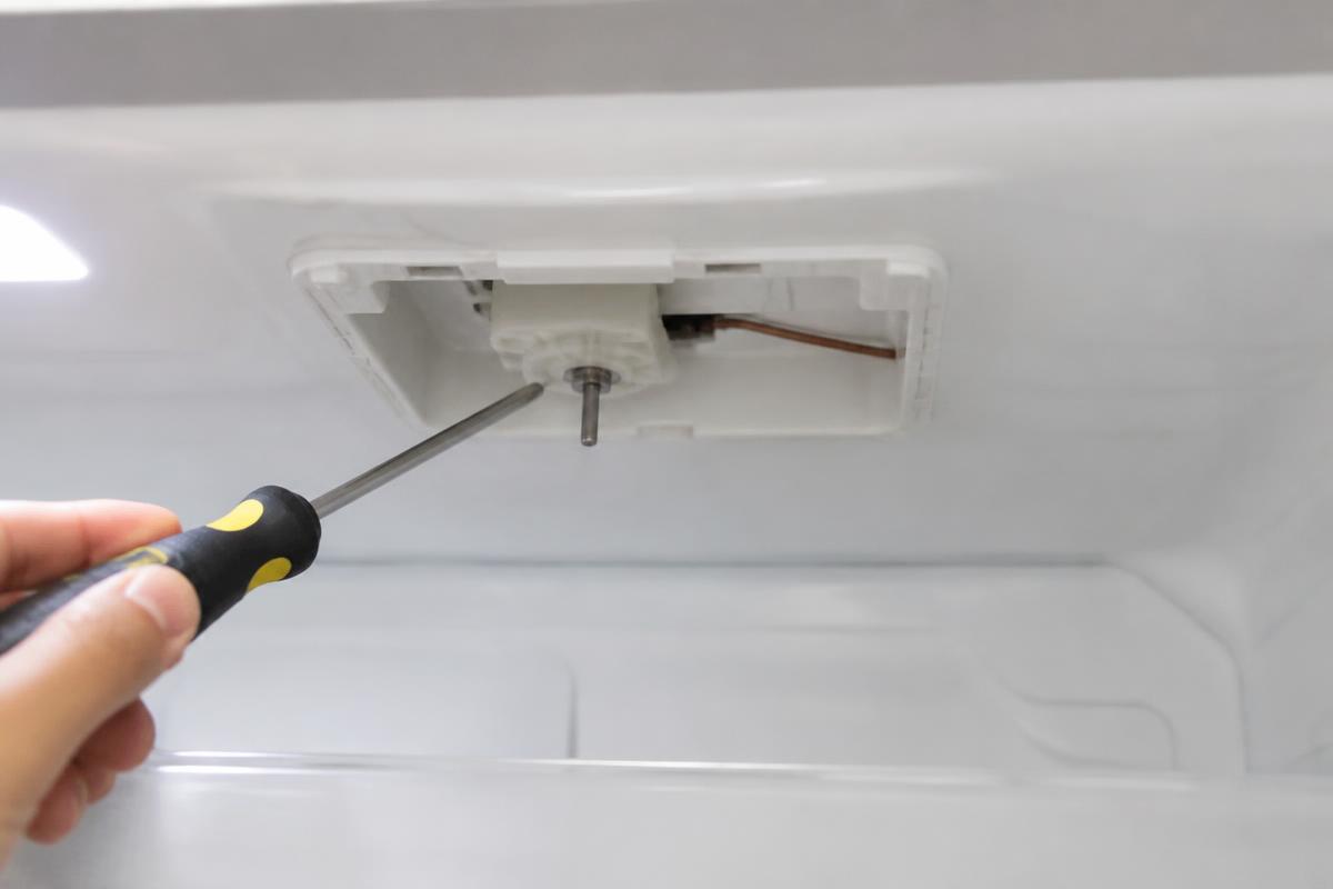 Console interno da geladeira com a tampa removida mostrando o termostato e o capilar de cobre